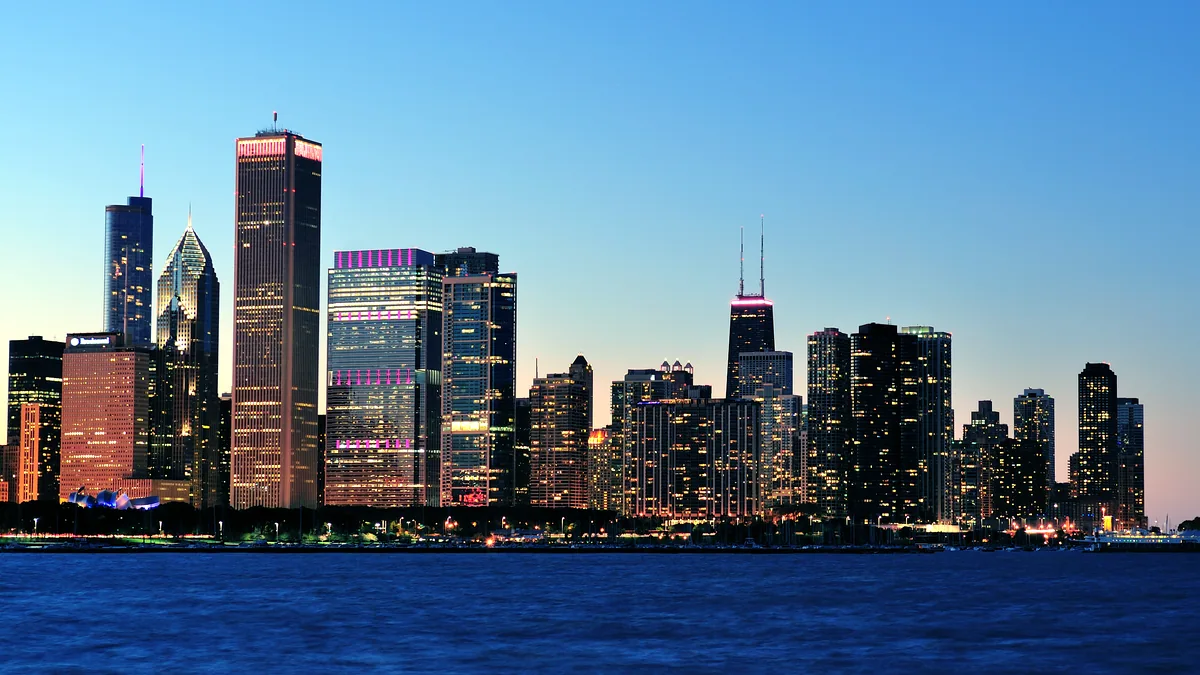 The Chicago lakefront skyline reflected in calm water at evening.