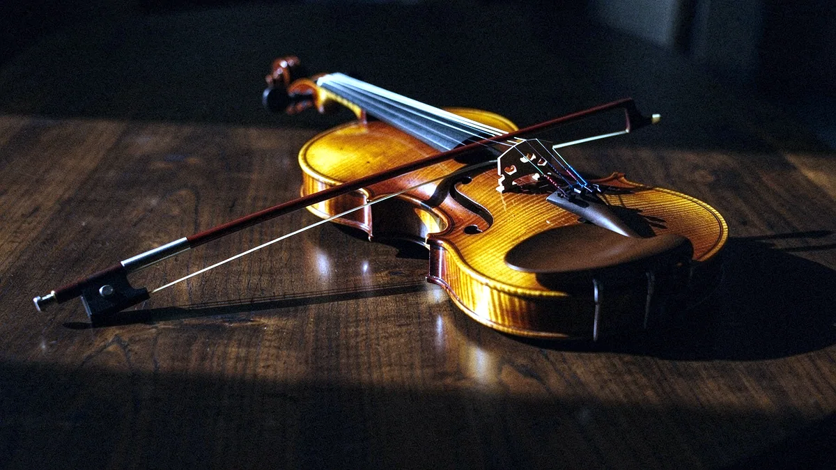Illustration: A folk fiddle and bow resting on a wooden table.