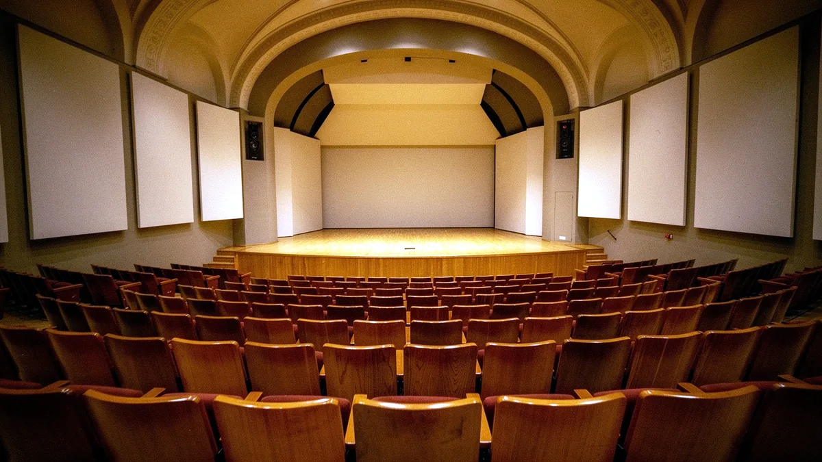 Illustration: A small concert hall with warm light over empty wooden seats.