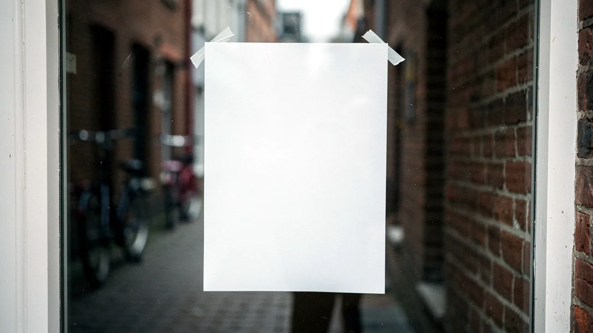 Illustration: A taped paper sign in a small shop window on a quiet street.